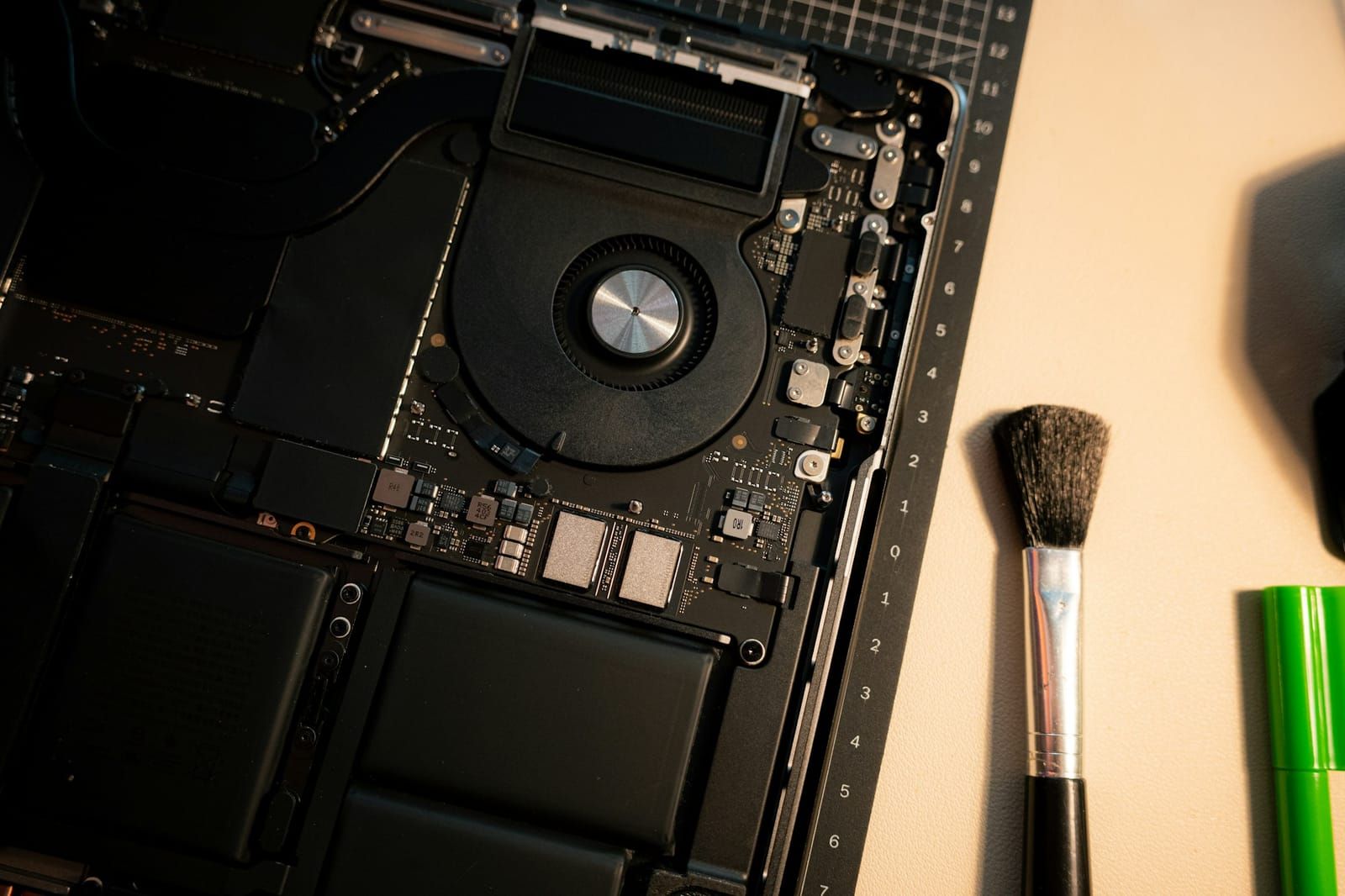 Geöffnetes MacBook mit Lüfter und Reinigungspinsel