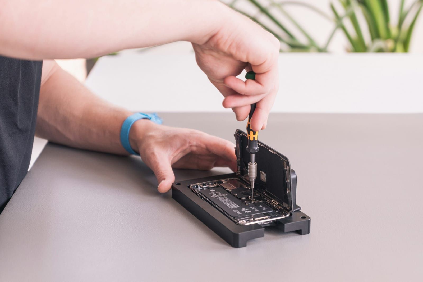 iPhone in einer Reparaturhalterung wird verschraubt