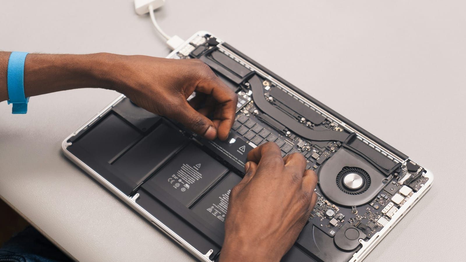 Hände bei der Reparatur eines geöffneten MacBook