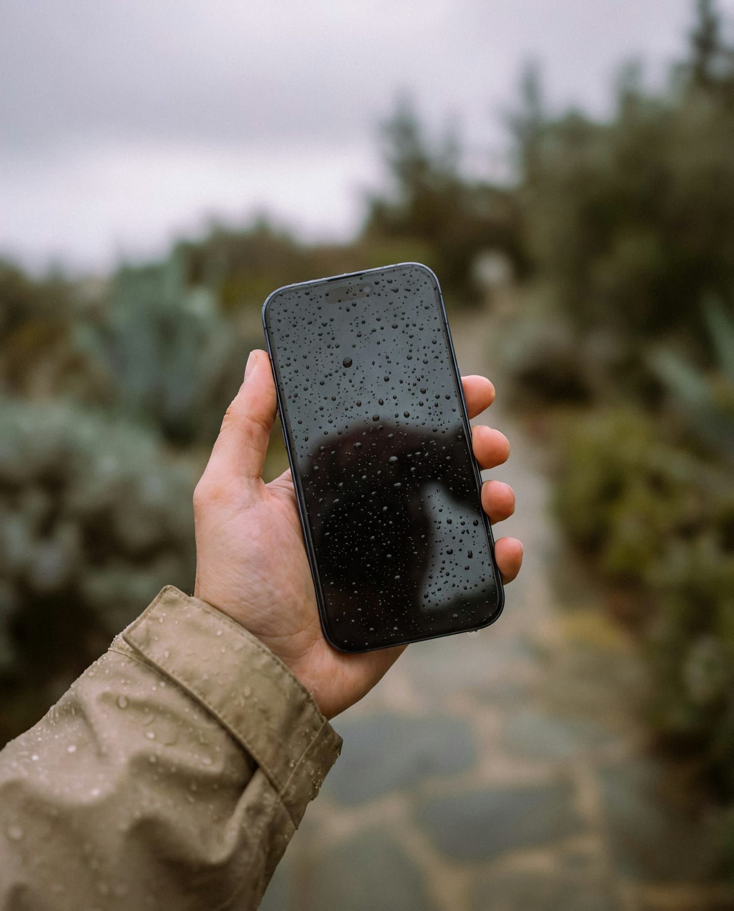 Nasses iPhone mit Wassertropfen in der Hand